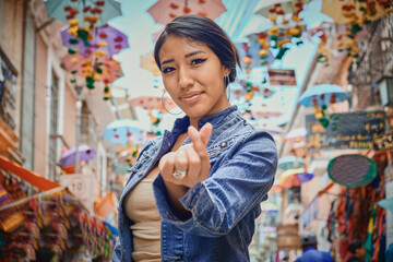 beautiful young latina tourist in the streets of la paz making a heart with her hand - travel concept - obrazy, fototapety, plakaty
