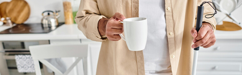cropped view of indian man with blindness in comfy outfit holding walking stick and cup of coffee