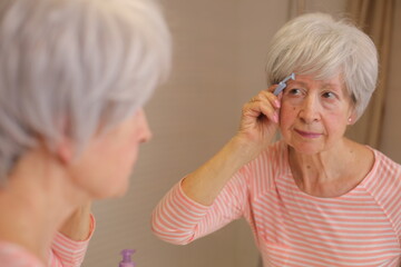 Senior woman using special shaving tool for the surroundings of the hairy eyebrows