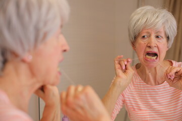 Senior woman presenting difficulties to floss her teeth 