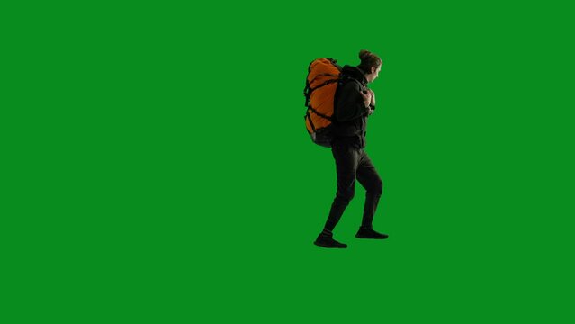 A male traveler with a backpack on his back and a retro camera around his neck climbs up on a green screen. After reaching the top, the happy man takes photos with the retro camera.