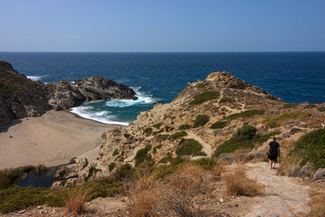 Back view of a vacationer walking to the beautiful Nas beach embedded in amazing canyon landscape.