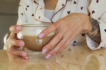 Kyiv, Ukraine - January 30, 2024: On a sunny winter morning, girls in a good mood in home clothes made themselves hot coffee and had breakfast. the girl has warm white pajamas with hearts