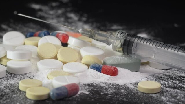 Syringe for injection and white powder cocaine powder and tablets, drugs concept and drug addiction