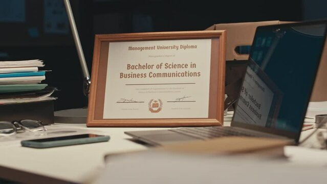 No people shot of diploma of Bachelor of Science in Business Communications in frame standing on office desk of businessmen out of workplace