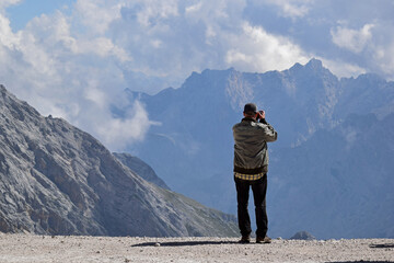 Fototapeta na wymiar mann vor einem abggrund fotografiert die wolkenverhangenen alpen