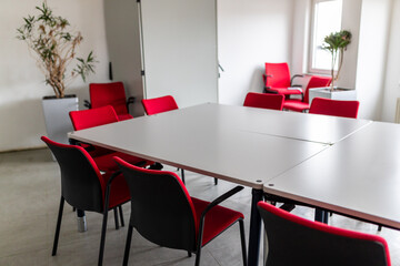 Pausenraum auf Arbeit mit Tischen und roten Stühlen