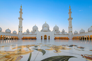 Interior courtyard of the Sheikh Zayed Grand Mosque, the largest mosque in the UAE, illuminated at twilight in Abu Dhabi, United Arab Emirates. - obrazy, fototapety, plakaty