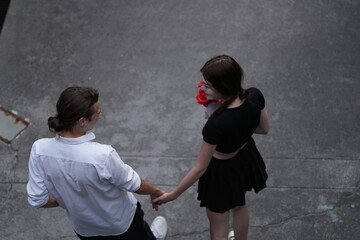top aerial view of couple young man and woman walking and holding the red bouquet rose flowers at outdoor street. Concept couple life with love and happy moment.