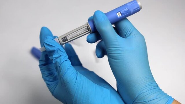 Hands in examination gloves demonstrate an injection with insulin for diabetics.