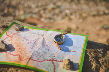 Close-up of an old compass and geographic map on a rock. Trip. Tourism