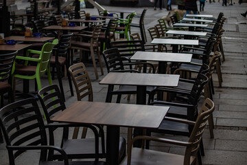 Empty chairs in coffee bar, outdoor seating but empty due to economic crisis and cold winter weather, on the streets of urban metropolis