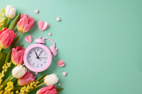 A spring affair: prepare to March 8th in celebration of women. Top view photo of alarm clock, tulips, mimosa, hearts on turquoise background with advert area