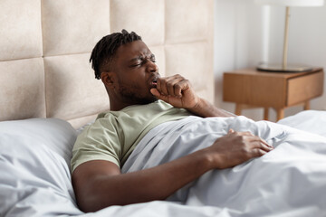 Sick Black Young Man Coughing In Fist Lying In Bed