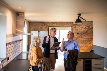 Senior couple looking at a house for purchase or lease with their real estate agent