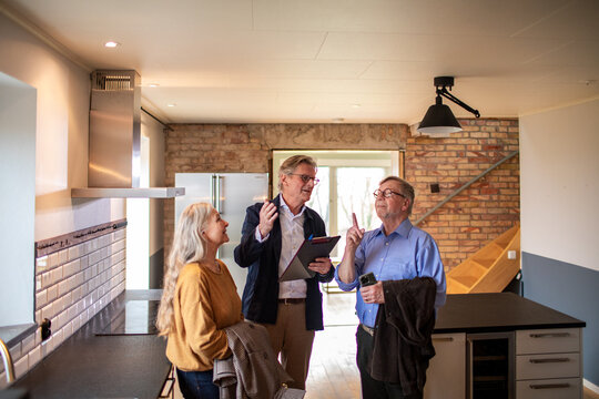 Senior couple looking at a house for purchase or lease with their real estate agent