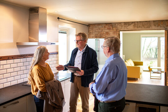 Senior couple looking at a house for purchase or lease with their real estate agent