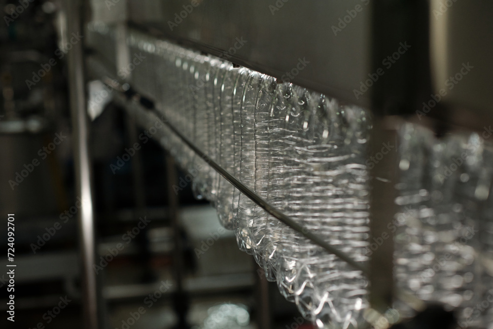 Aufkleber row of clean empty transparent plastic bottles moving along belt conveyor or production line inside 