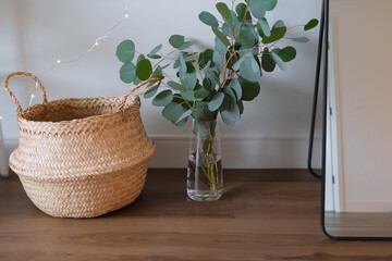 cozy home interior details with eucalyptus and straw basket, eco-style decor