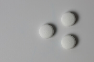 Three white pills on a white background