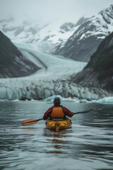 A man paddling in a kayak through the glacial lake with glacier in background