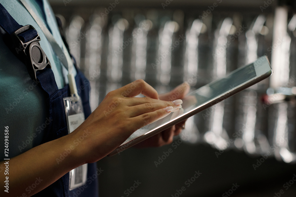 Aufkleber hand of young female engineer of factory scrolling on tablet screen against assembly line or conveyo