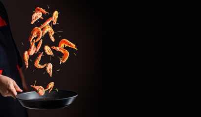 cooking shrimp in pan. Chef cooking prawn on a dark background. copy space for text