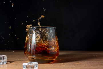 Splashes of cognac in a glass with ice
