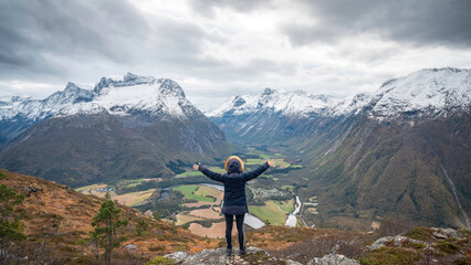 Traveler with his back turned, hands open, enjoying a mountain landscape in the Norwegian fjords of the city of Andalsnes, Norway.