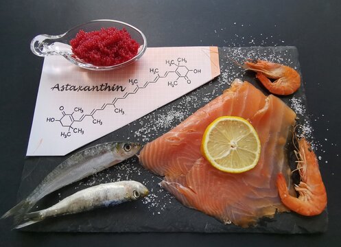 Food rich in astaxanthin with structural chemical formula of astaxanthin. Natural sources of astaxanthin: salmon, caviar, trout, shrimps, fish. Astaxanthin is a red pigment, carotenoid and antioxidant