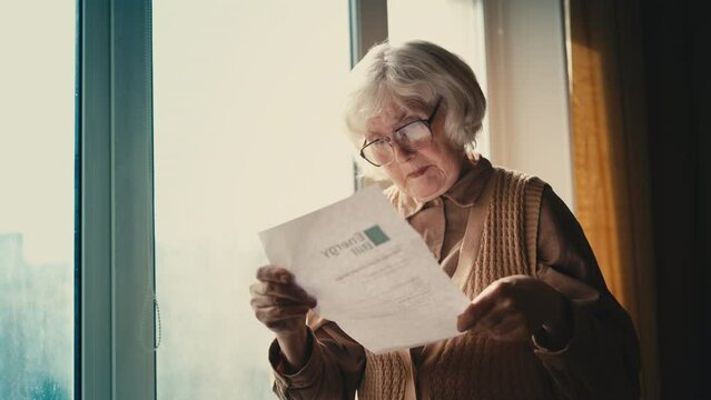 Grandmother opening letter with energy bill, pleased with a service discount