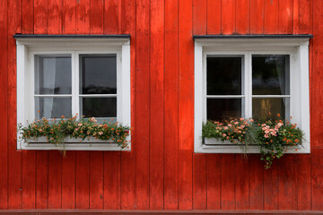 White windows with flowers on red wooden wall in Porvoo, Finland - 724131770