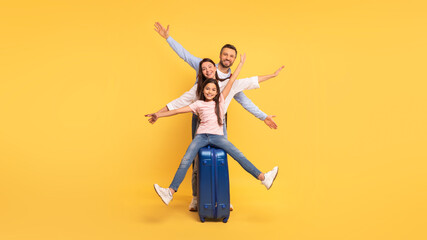 Happy Parents And Little Daughter Posing With Travel Suitcase, Studio
