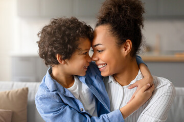 Black mother and son sharing joyous forehead touch at home