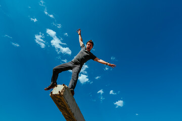 Young emotional man balancing on sky backgrounds