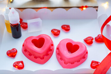 Handmade homemade soap in the shape of hearts for a Valentine's Day gift to your beloved. Perfumes and dyes, soap base on the table