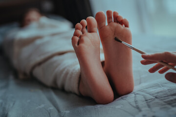 Woman's hand brushes feet of sleeping baby