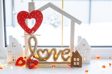 Key to tiny house of cozy home with Valentine decor on the windowsill. Gift for valentines day, family love nest. design, project, moving to new house, mortgage, rent and purchase real estate