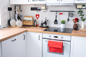 The interior of the kitchen in the house is decorated with red hearts for Valentine's Day. Decor on the table, stove, utensils, festive mood in a family nest