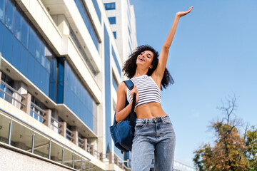 Photo of cheerful glad positive girl raise hand walk after university lectures relax rest free time spring outside