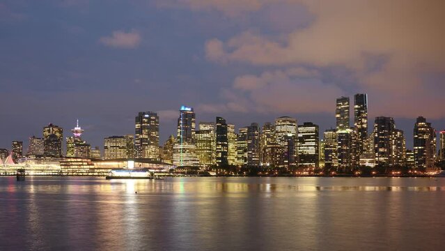 View of buildings illuminated in the city on coastline from stanley park at Vancouver