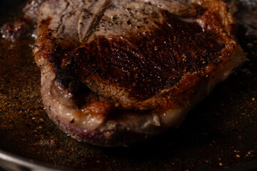 Beef steak cooking at high temperature in a frying pan.