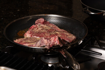 Beef steak cooking at high temperature in a frying pan.