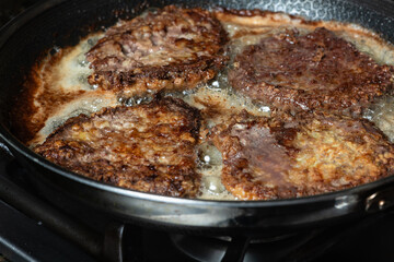 Frying schnitzel in a pan on gas cook top. Home cooking concept.