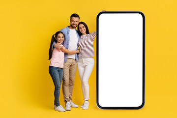 Happy Caucasian Family Standing Near Big Smartphone With Blank Screen