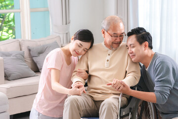 Happy elder Asian man using wheelchair while exercise indoor house with his son taking care of him...
