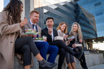 group of happy business people eating salad and healthy food outside