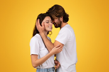 Intimate couple in white t-shirts share a tender moment, with the man gently cradling the woman's face