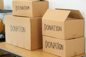 Cardboard boxes with donated goods in office of charity organization - obrazy, fototapety, plakaty