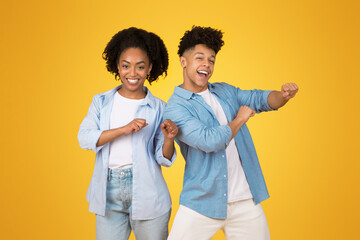 Two joyful African American teenagers dancing, with the young woman in a light blue shirt